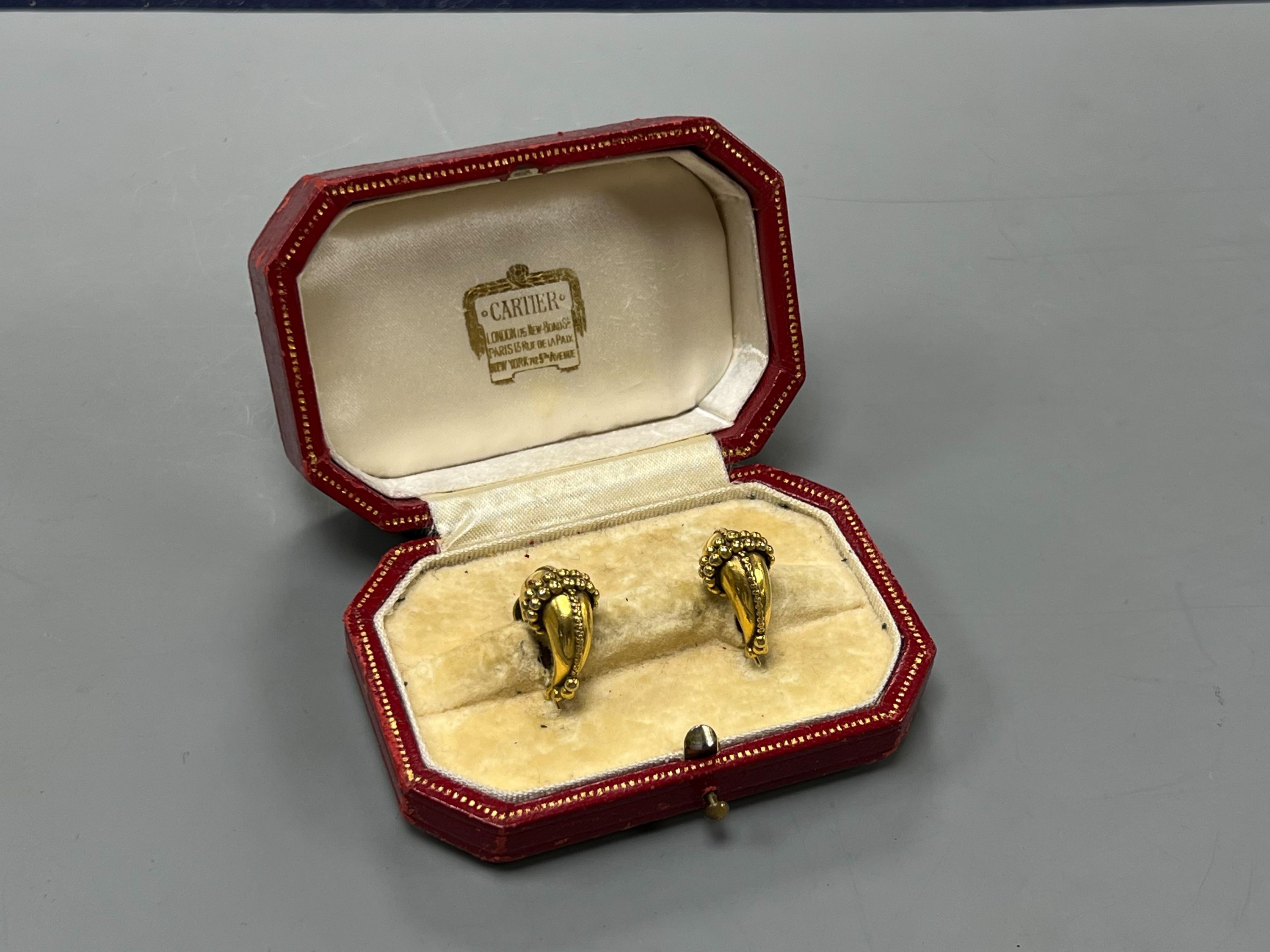 A modern pair of gilt metal earrings, together with a Cartier gilt tooled red leather jewellery box.